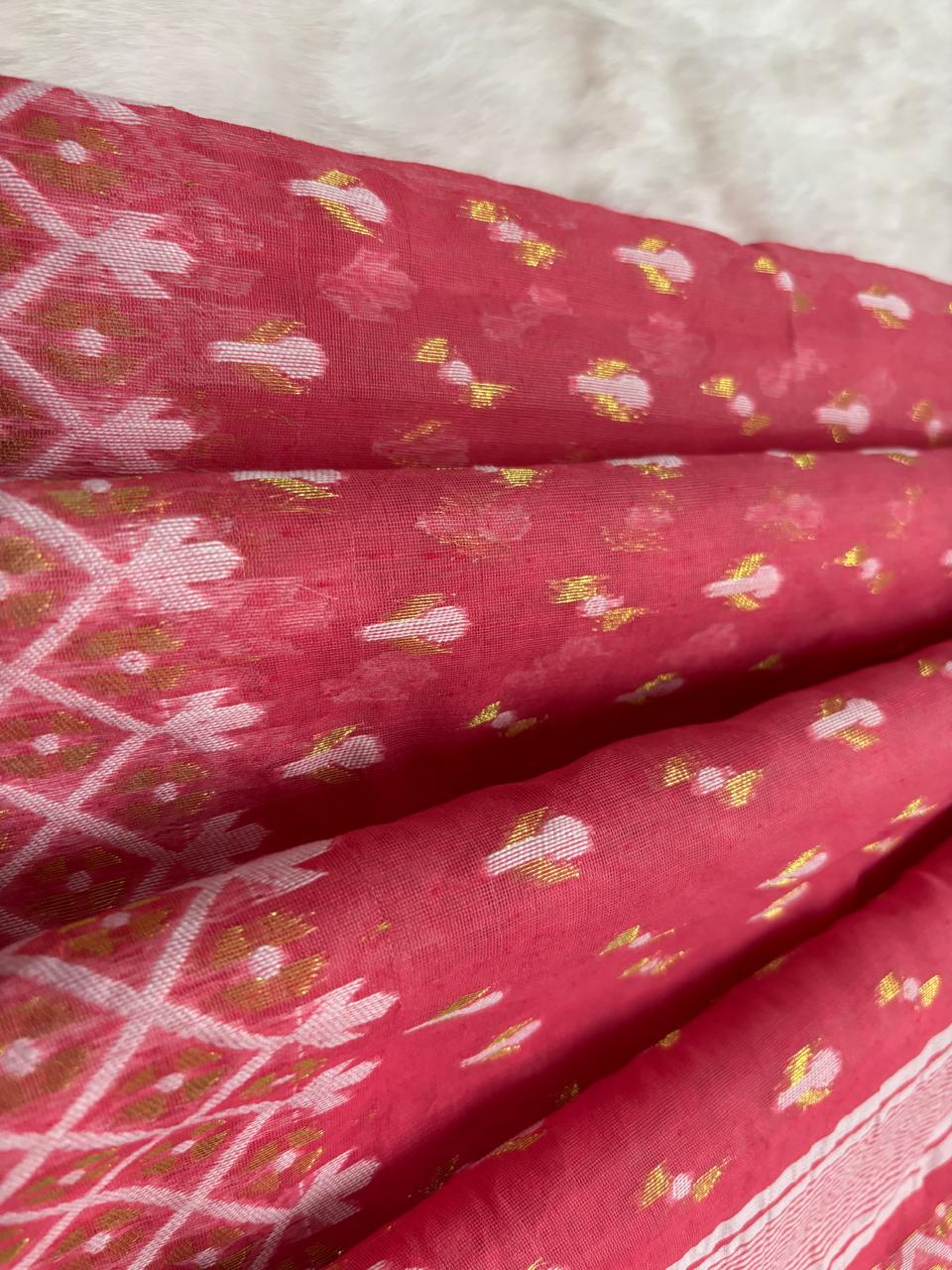 Pink fabric with white and gold patterns on a textured light gray background