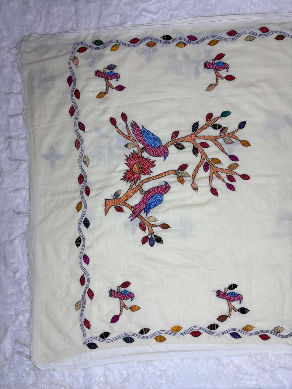 Embroidered fabric with colorful bird design on a white background