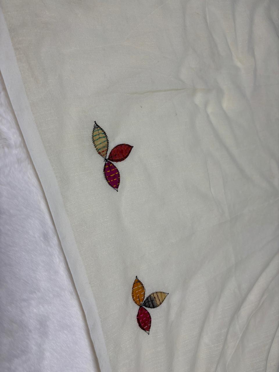 Colorful embroidered leaves on a white fabric background