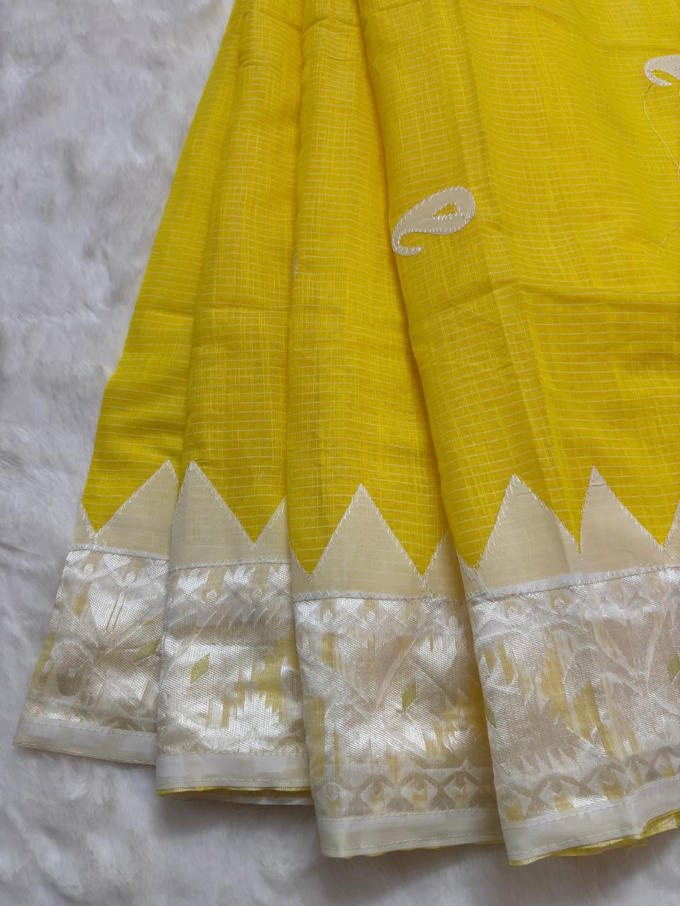Yellow saree with white border on a textured surface