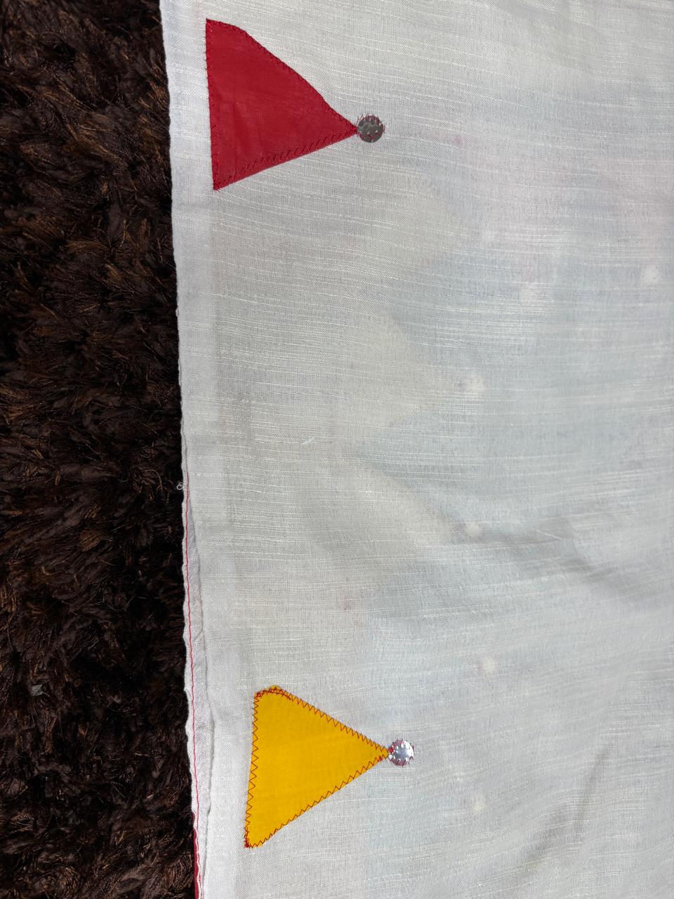 Close-up of a fabric with red and yellow triangles on a textured surface
