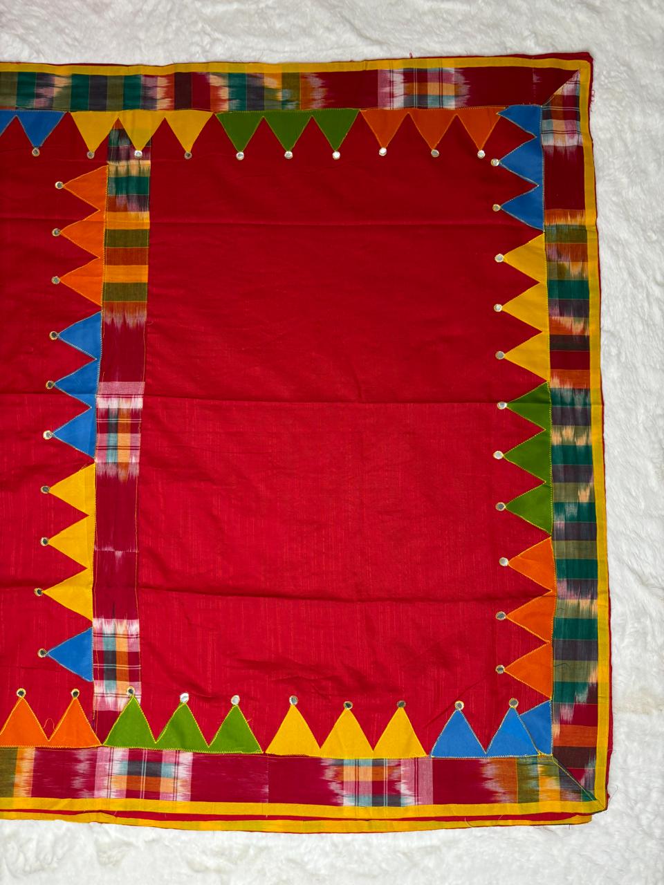 Red fabric with colorful geometric border on a white background